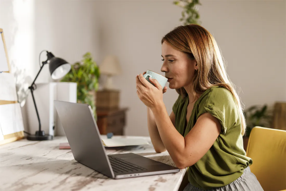 a woman sips coffee at her computer